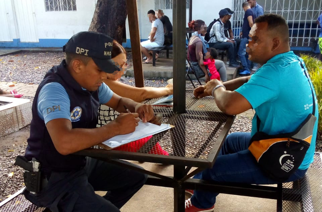 Un policier parle à des migrants au Honduras.